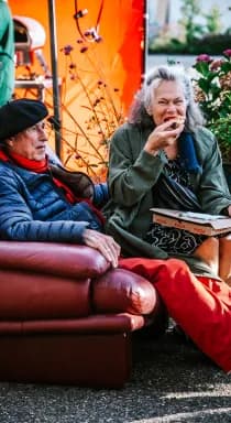 Twee gasten met een drankje op een bank in de buitenlucht