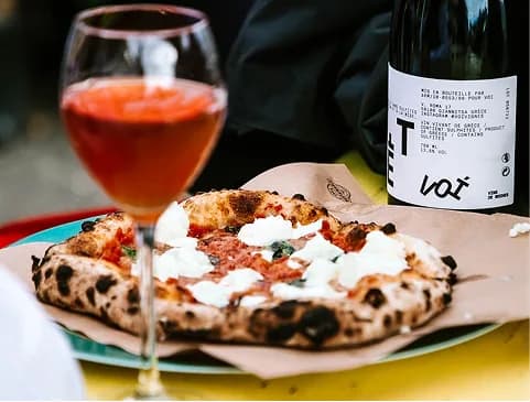 Pizza met mozzarella naast een glas rosé en een fles wijn