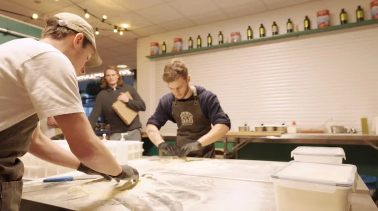 Pizzabakkers werken het deeg op een met bloem bestoven tafel
