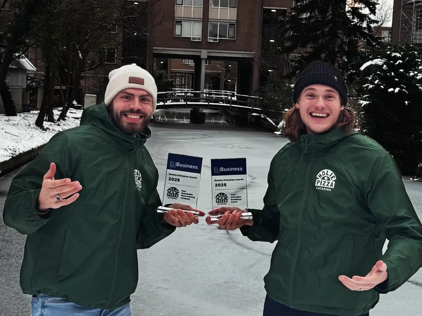 De twee oprichters van Holie Pizza met hun twee EU Business Awards in de sneeuw
