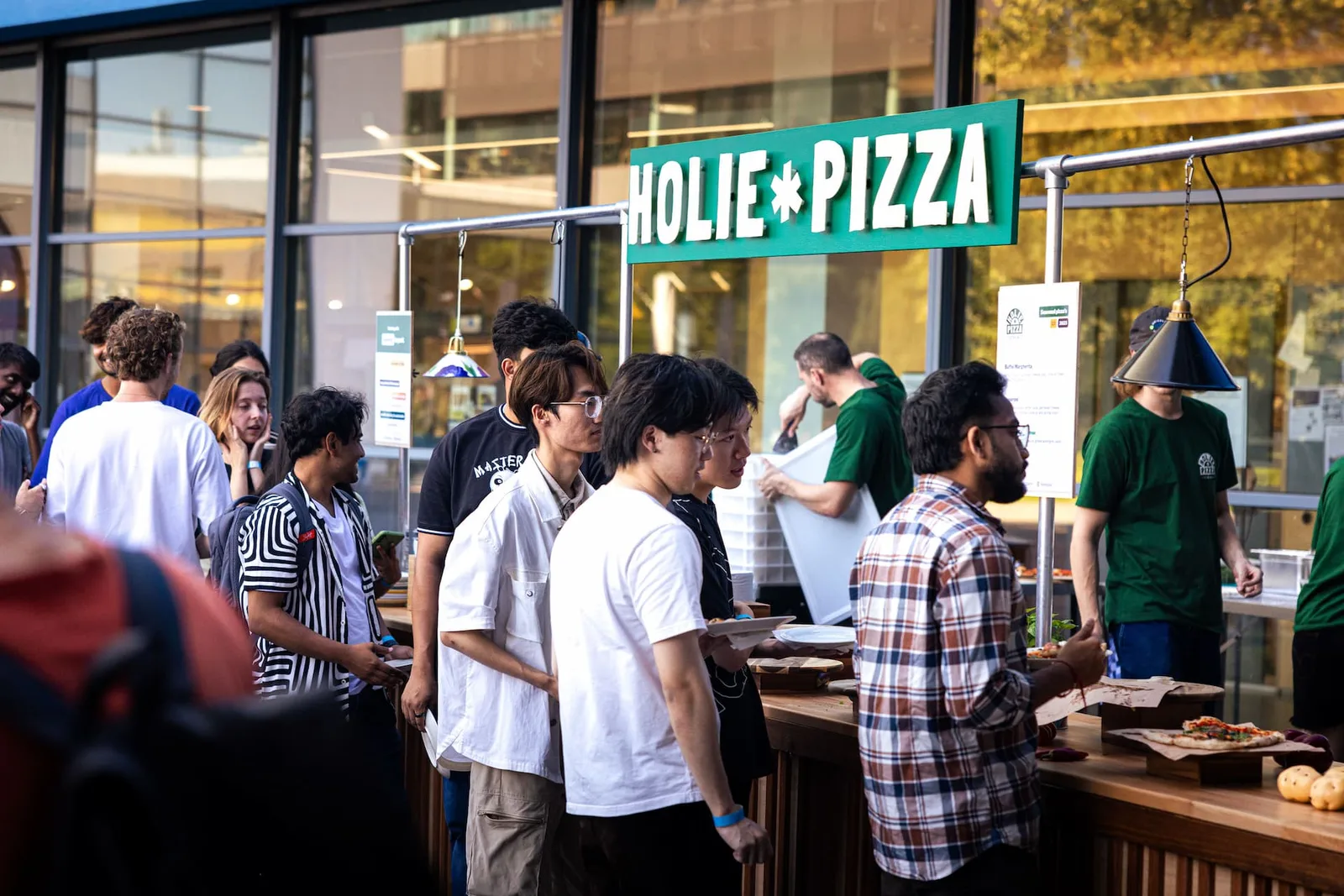 Gasten in de rij bij de buitenopstelling van Holie Pizza